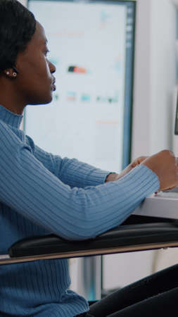 Black paralized invalid handicapped employee discussing with remote manager using video call talking online company problems during virtual meeting sitting in wheelchair. strat up business office.の写真素材