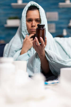 Person with sickness holding bottle of capsules pills antibiotic. Caucasian woman taking medical treatment vitamin drugs capsules for illness healthcare. Headache remedyの写真素材