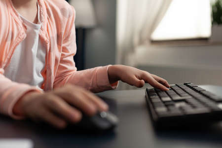 Close up of student hand typing on computer keyboard technology for online internet connection class. Smart little girl using digital devices for schoolwork and education knowledgeの写真素材