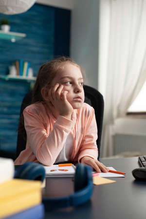 Young student getting online education from home while paying attention to class lesson and notebook...