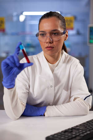 Chemical industry woman working with blood sample flask for treatment development test. Professional...