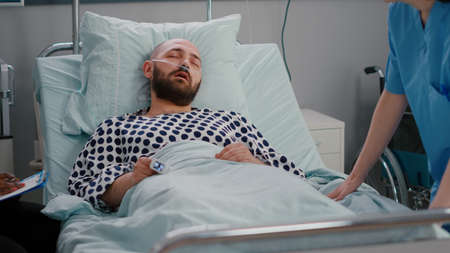 Medical nurse checking temperature monitoring sickness symptom during recovery appointment in...