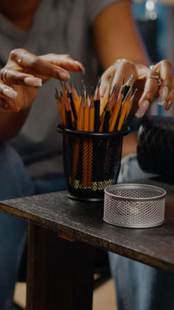 Close up of art tools and pencils on table in artwork space at home. Disabled african american...