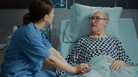 Nurse from hospital ward tends to sick old patient in bed assuring healing from disease, illness....