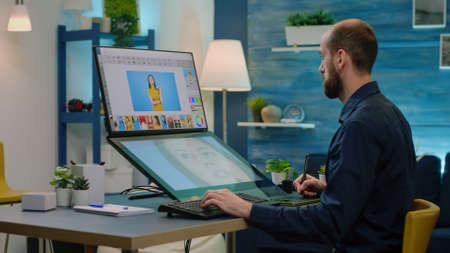 Man photographer retouching pictures on editing software with touch screen. Media artist using computer to retouch photos for photography project. Editor with graphic tablet and stylusの写真素材
