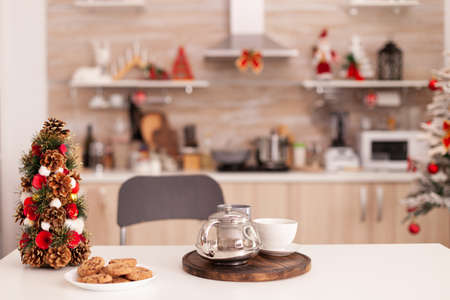 Empty xmas decorated culinary kitchen with nobody in it ready for christmas holiday. On table standing baked homemade delicious cookie and cup of coffee waiting for traditional morning dessertの写真素材