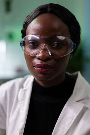 Portrait of african american biologist doctor looking into camera working in biological hospital laboratory. Medical team analyzing genetically modified plant during agriculture experimentの写真素材