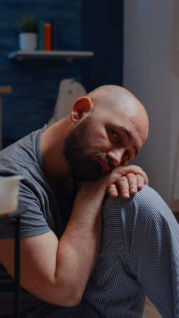 Unhappy alone depressed man sitting on floor looking at camera with sad, dissapointed expression suffering from depression psychological problem bipolar disorder loneliness, frustration anxiety.の写真素材