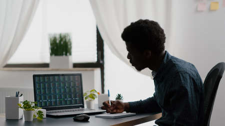 African american man analysing crypto currency stock markets trading checking stock ticker index, deciding to buy or sell digital coin money. Watching bitcoin charts forex investment finance exchangeの写真素材