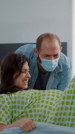 Multi ethnic people delivering child in hospital ward at maternity. Pregnant woman in labor pushing, giving birth while husband, obstetrics doctor and african american nurse helping patientの写真素材