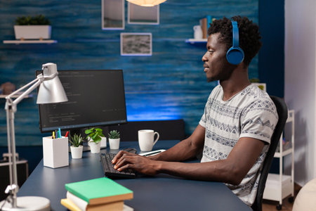 African american it employee with headset working remote from home at website design using programming technologies on computer. Programmer man coding digital business server. Cyber securityの写真素材