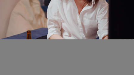 Young woman bringing pizza in living room on table to eat while watching television after work. Hungry person with snacks, fast food meal and bottle of beer enjoying takeaway food at homeの写真素材