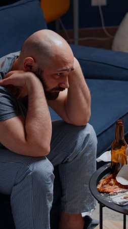 Psychotic alone unhappy, depressed, frustrated man sitting in sofa feeling disappointed and vulnerable, suffering from insomnia, stress anxiety, mental problems, suicidal thoughts, chronic diseaseの写真素材