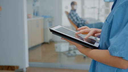 Close up of modern tablet with touchscreen and nurse hand using digital technology for development....