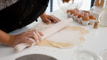Close up of children hand preparing homemade gingerbread making cookies dough using traditional...