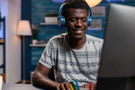 Smiling african american freelancer with headphones typing management ideas on computer working...