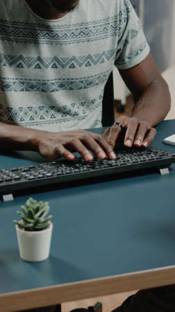 Close up of african american hands typing on computer keyboard for business remote work. Black person working from home with gadgets and technology at desk with notebook. Afro entrepreneurの写真素材