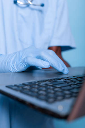 Close up of nurse hand with gloves using laptop in studio with isolated background. Medical...