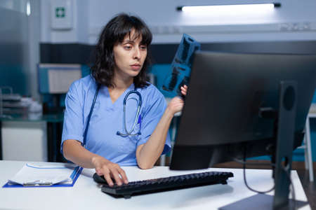Nurse analyzing radiography for medical diagnosis, doing overtime work. Assistant looking at x ray...