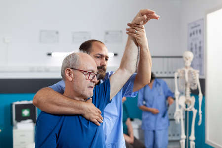 Osteopathy assistant stretching arm and shoulder of patient with muscle pain for physiotherapy....