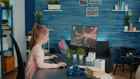 Frustrated child losing at video games on computer after homework and online courses. Little girl...