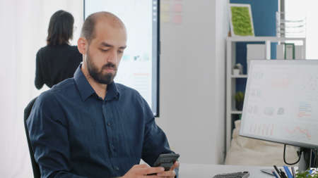 Close up of businessman using smartphone with touch screen at office. Man with corporate job holding...