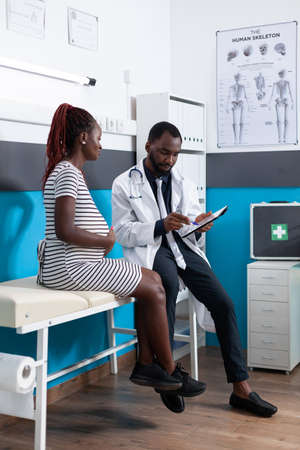 Woman expecting child and doing examination with specialist in medical office. General practitioner consulting patient to check pregnancy healthcare, preparing mother to give birthの写真素材