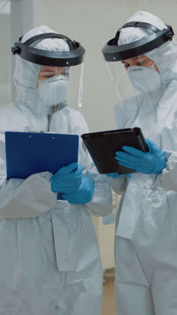 Dentist giving tablet to dental nurse before consultation appointment with patient. Stomatology...