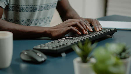 Close up of hands using computer keyboard and listening to music for business remote work. Man dancing and singing while working from home with technology. Worker having fun at deskの写真素材