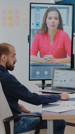 Colleagues talking to woman on video call for business meeting in boardroom. Workmates using...