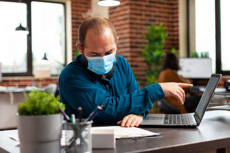 Businessman wearing medical protective face mask to prevent infection with virus planning company...