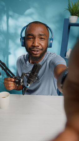 Vertical video: POV of vlogger holding camera to film video in studio. Social media influencer vlogging for content on channel. Blogger using modern equipment to record vlog for subscribersの写真素材