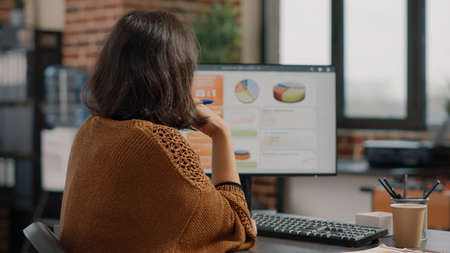 Business woman analyzing rate charts on computer and files to plan project and strategy. Employee...
