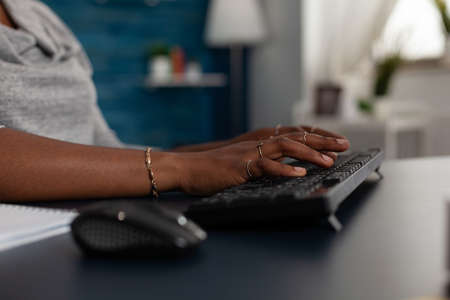 Close up of hands using keyboard to work on computer at desk. Young woman working on business project with modern device and technology at home, browsing online internet webiste.の写真素材