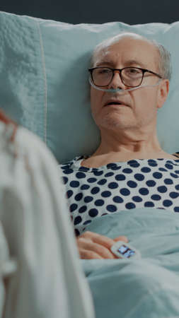 Sick patient with disease listening to advice from doctor in hospital ward at medical facility. African american specialist consulting old man to get treatment for curing diseaseの写真素材