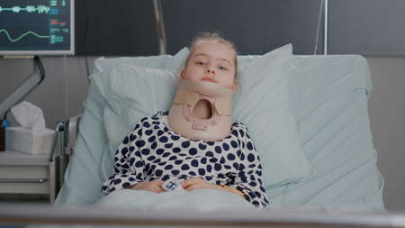 Portrait of hospitalized sick little child resting in bed wearing medical neck cervical collar...
