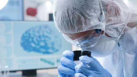 Closeup of scientist man in ppe equipment analyzing blood sample using medical microscope developing...