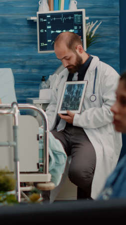 Retired patient with disease looking at tablet with x ray scan for osteopathy diagnosis in nursing...