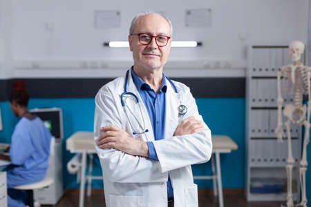 Portrait of smiling medic with white coat and stethoscope standing with arms crossed. Healthcare specialist being ready for consultation and examination with patient, giving medical advice.の写真素材
