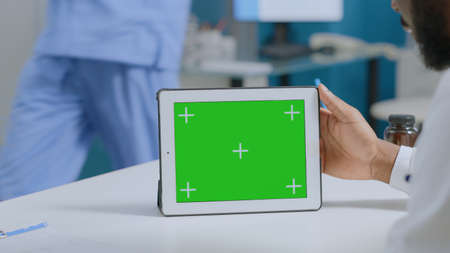 African american man analyzing medical expertise working at sickness report in hospital office. Mock up green screen chroma key tablet computer with isolated display. Medicine servicesの写真素材