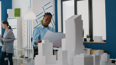 Woman builder analyzing blueprints plans to design layout of construction site and building model....