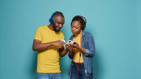 Couple wearing headphones and listening to music with mobile phone. Man and woman enjoying...