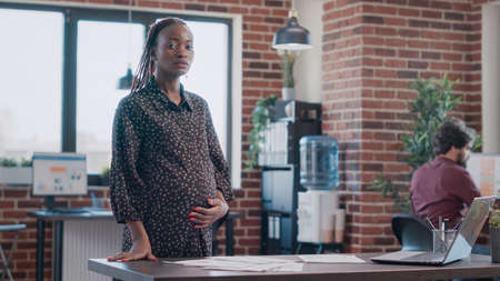 POV of pregnant business woman talking on video call in office. Entrepreneur expecting child and using online video conference on internet to discuss project planning and strategy.の写真素材