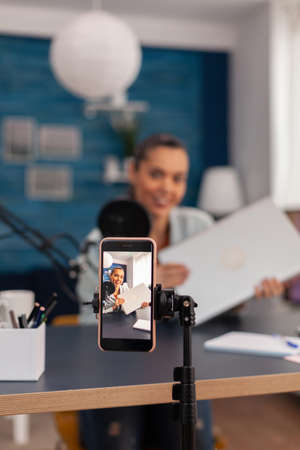 Closeup of smartphone recording product review. Mobile phone filming woman presenter doing vlog...