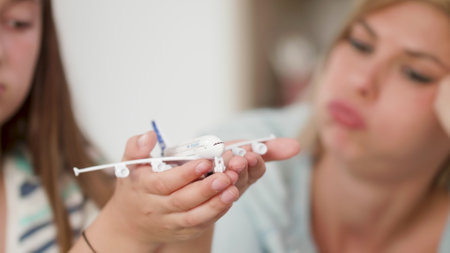 Closeup of mother and daughter holding toy plane dreaming at summer holiday destination during...