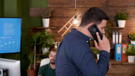 Businessman talking at phone discussing project implementation with remote manager explaining company strategy. Executive manager working at marketing strategy in startup business officeの写真素材