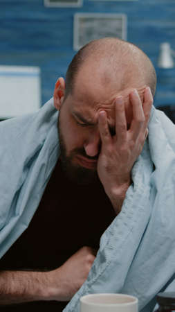 Close up of sick man blowing runny nose with tissues and sneezing because of disease. Ill adult with cold and flu having headache and chills. Unwell person with virus symptoms.の写真素材