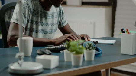 African american man with headphones listening to music while working from home on computer. Black freelancer dancing and having fun while doing remote work for freelance businessの写真素材