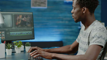 Close up of black videographer working with video editing software to design montage. African american media editor retouching musical footage with visual and audio effects for contentの写真素材