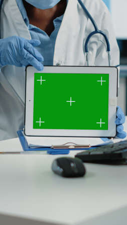 Close up of horizontal green screen on digital tablet in cabinet. Doctor holding gadget with isolated template and mockup background for chroma key and technology at checkup visit.の写真素材